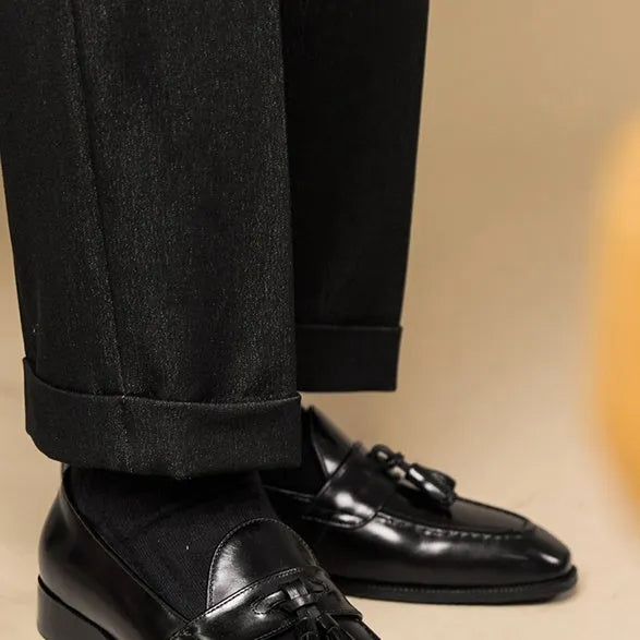 Men's black and brown genuine leather tassel loafers on a white background.