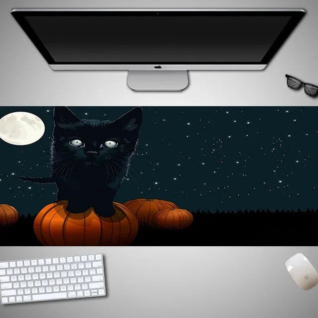 Oversized rectangular Halloween-themed mouse pad on a desk, showing one of 28 graphic designs.