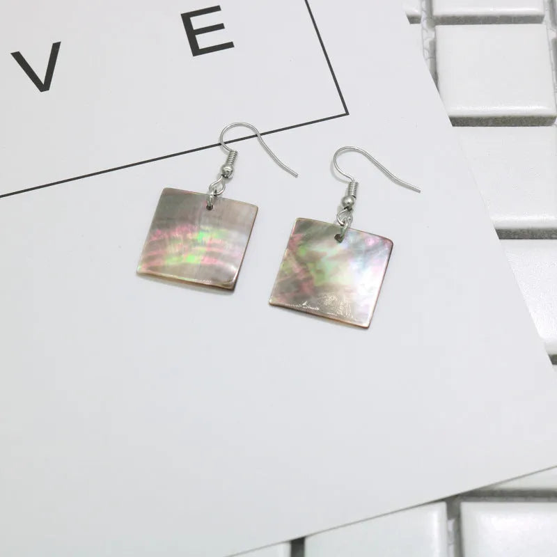 Handmade women's shell earrings in rectangular and square geometric shapes on a neutral background.