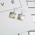 Handmade women's shell earrings in rectangular and square geometric shapes on a neutral background.