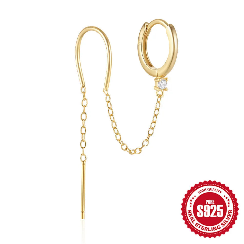 Close-up of a sterling silver stud earring with a geometric flower shape and dangling gold-tone tassel and chain details.