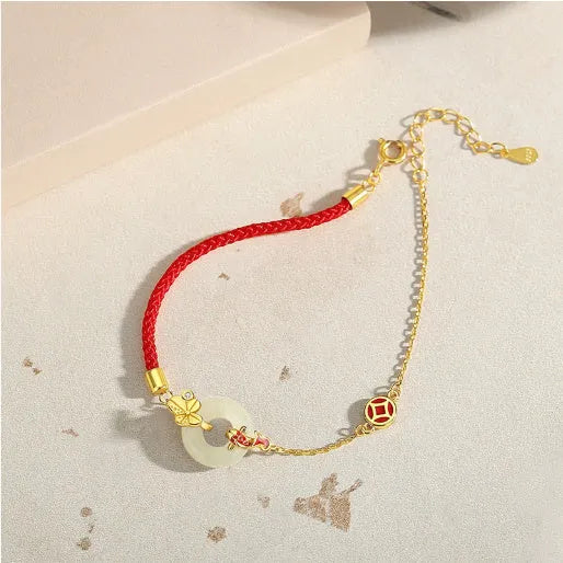 Close-up of a women's retro bracelet with a Hetian Jade stone, red cord, and a gold Koi fish safety buckle on a 925 silver chain.