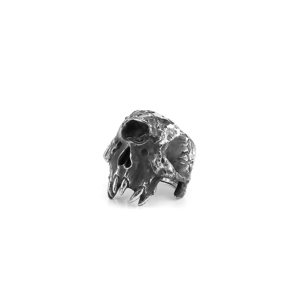 Close-up of a silver-toned alloy ring with a detailed one-eyed skull design on a black background.