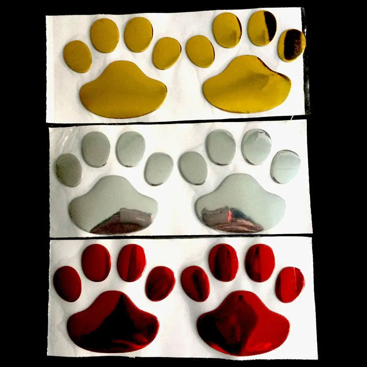 Close-up of a black PVC car sticker with dog footprints and a hand-shaped brush texture on a car bumper.