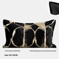 Black and gold abstract patterned square decorative pillow with a flannel cover on a grey sofa.