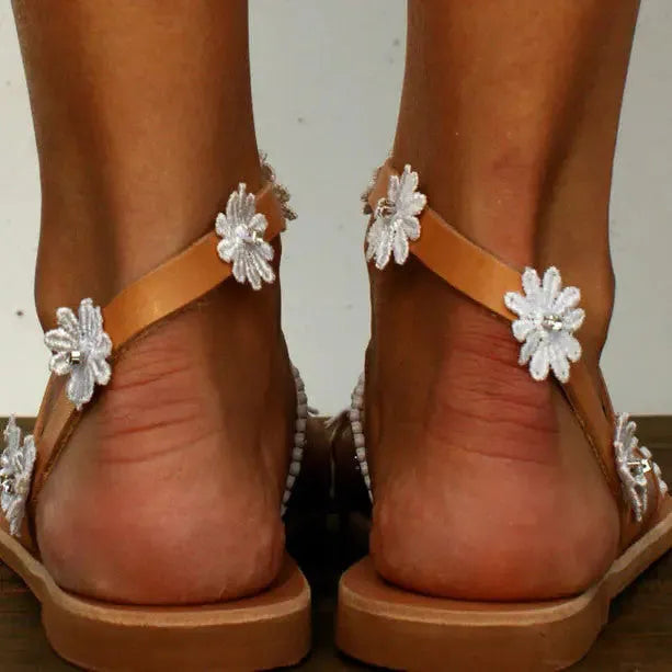 Brown women's flat sandals with decorative flowers and a herringbone toe shape on a rubber sole.