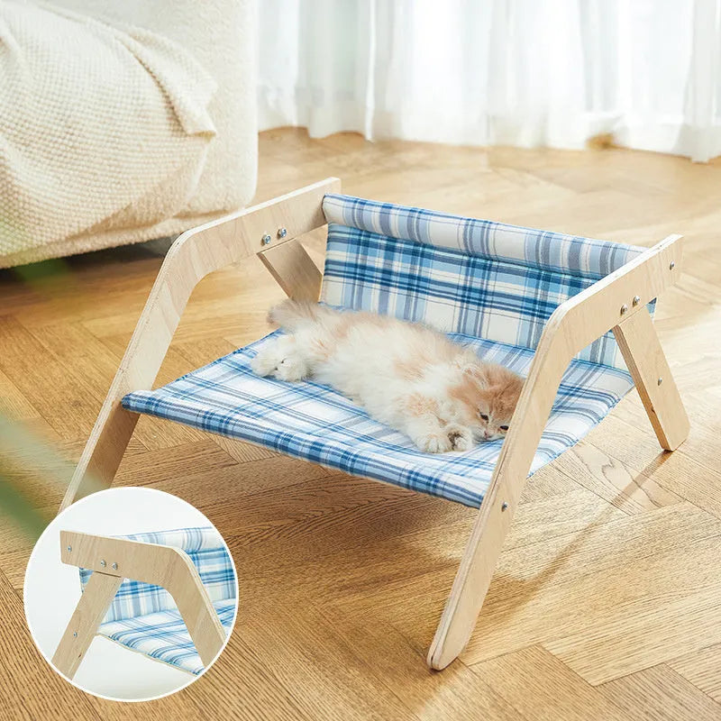 Wooden framed elevated cat bed with blue cloth hammock in beach chair style.