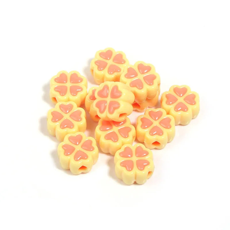 Assortment of frosted acrylic love clover beads in mixed colours on a white background.