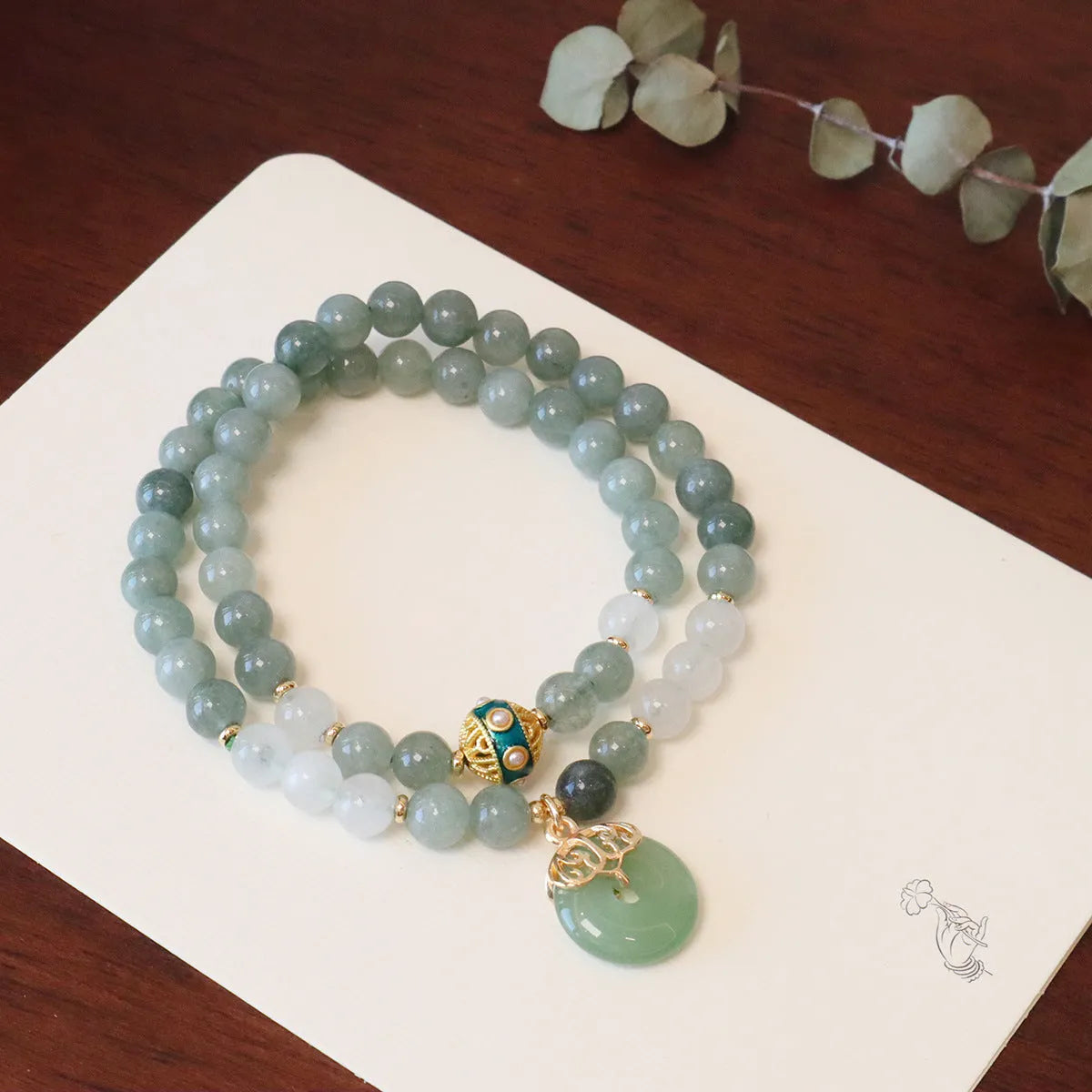 Close-up of a women's Myanmar jade bracelet with a traditional Chinese safety buckle pendant and geometric lucky bead charm.