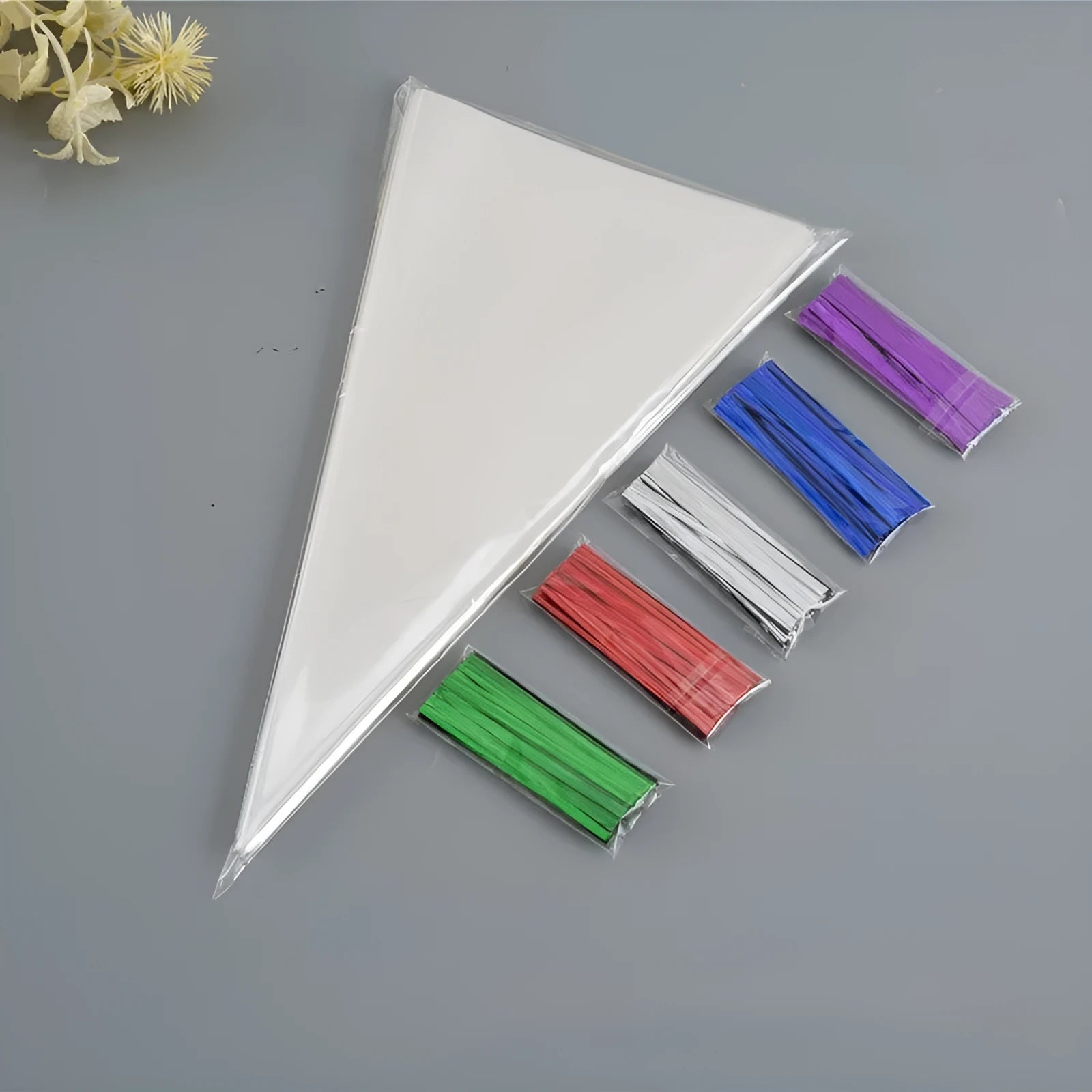 Clear triangle-shaped plastic packaging bags with a twisted wire tie closure on a white background.