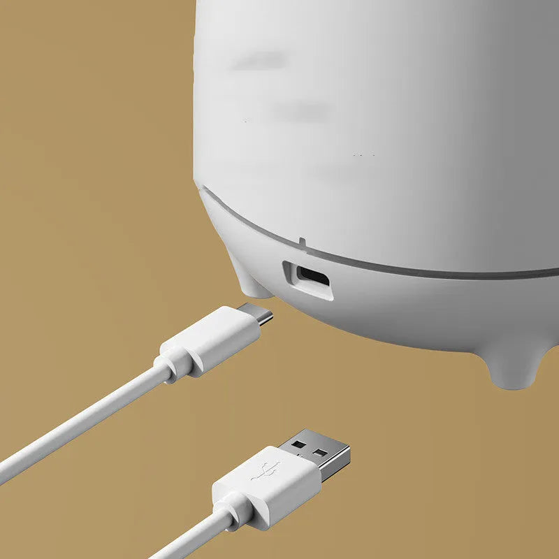 White volcanic-shaped ultrasonic humidifier and essential oil diffuser with USB cable on a wooden table.