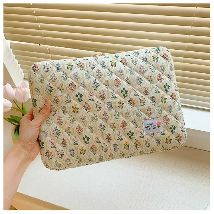 Printed cloth laptop bag showing floral and heart patterns in green, pink, and red colourways