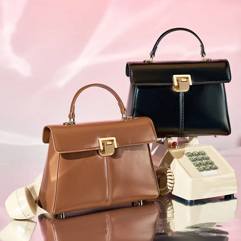 Women's black leather shoulder bag with vachette clasp showing horizontal square shape and shoulder strap