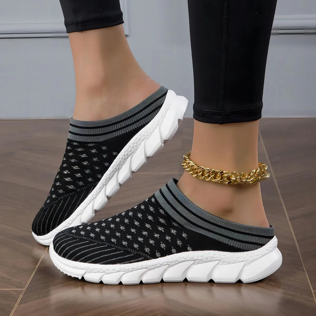 Women's black Flyknit slipper sock with striped pattern and hollowed-out design on a solid background.