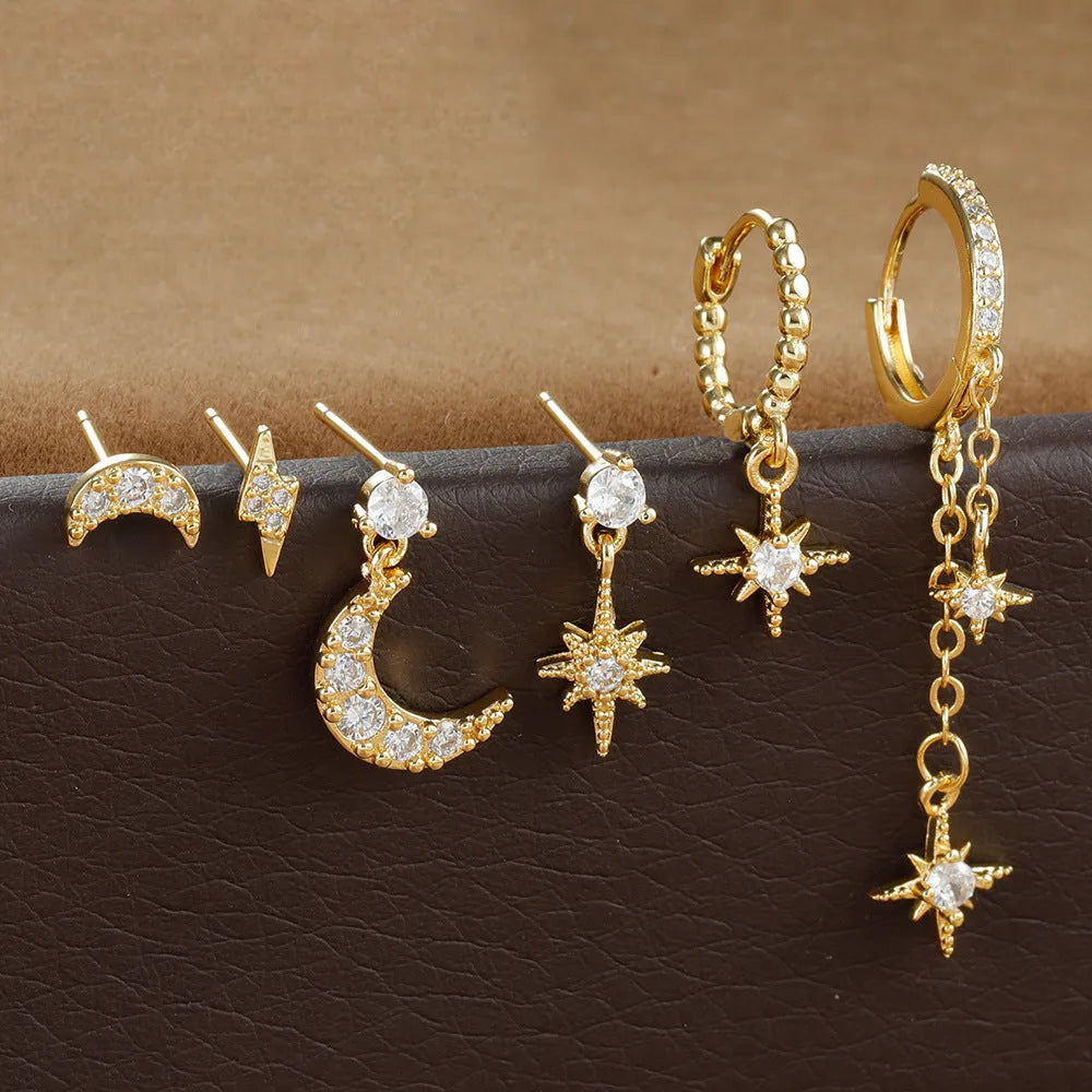 Set of six gold electroplated earrings with zircon studs and chain tassels on a flat surface.