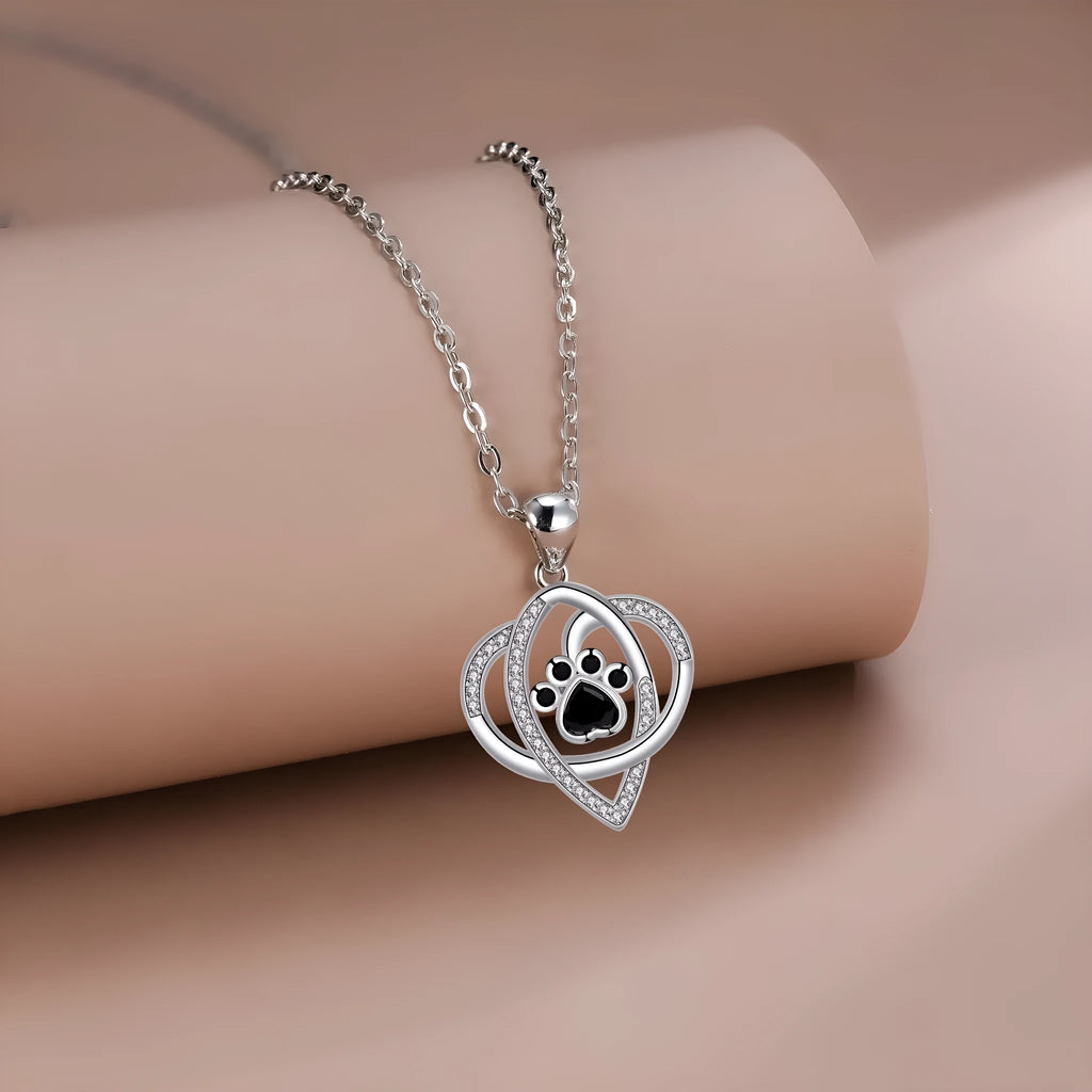 Light gold necklace with a pendant showing raised dog and cat paw prints on a cross chain.