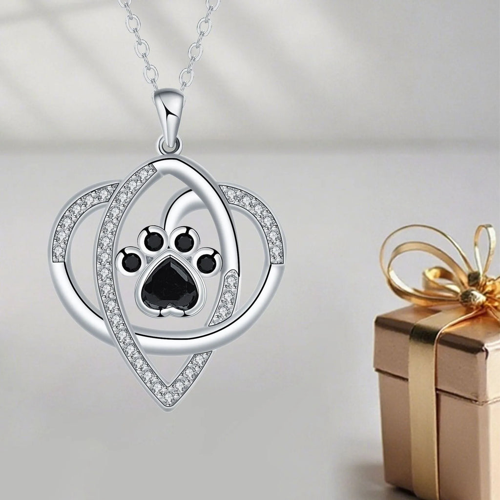 Light gold necklace with a pendant showing raised dog and cat paw prints on a cross chain.