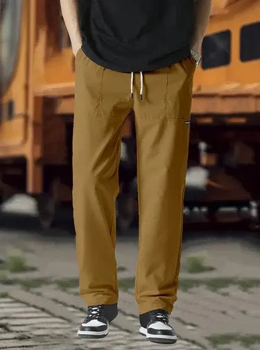 Men's light grey tapered slim-fit trousers with an elastic waistband on a hanger.
