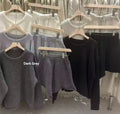 Woman wearing a loose grey long sleeve sweater and matching wide leg knit shorts lounge set.
