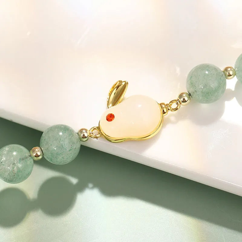 Women's rabbit charm bracelet with green aventurine or strawberry quartz beads, copper and gold accents.