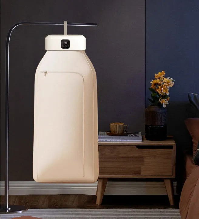White cylindrical portable mini clothes dryer with remote control on a table.
