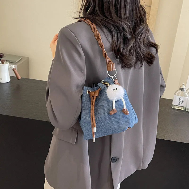 Blue synthetic leather cross body bucket bag with medium-soft structure and optional hanging ornaments