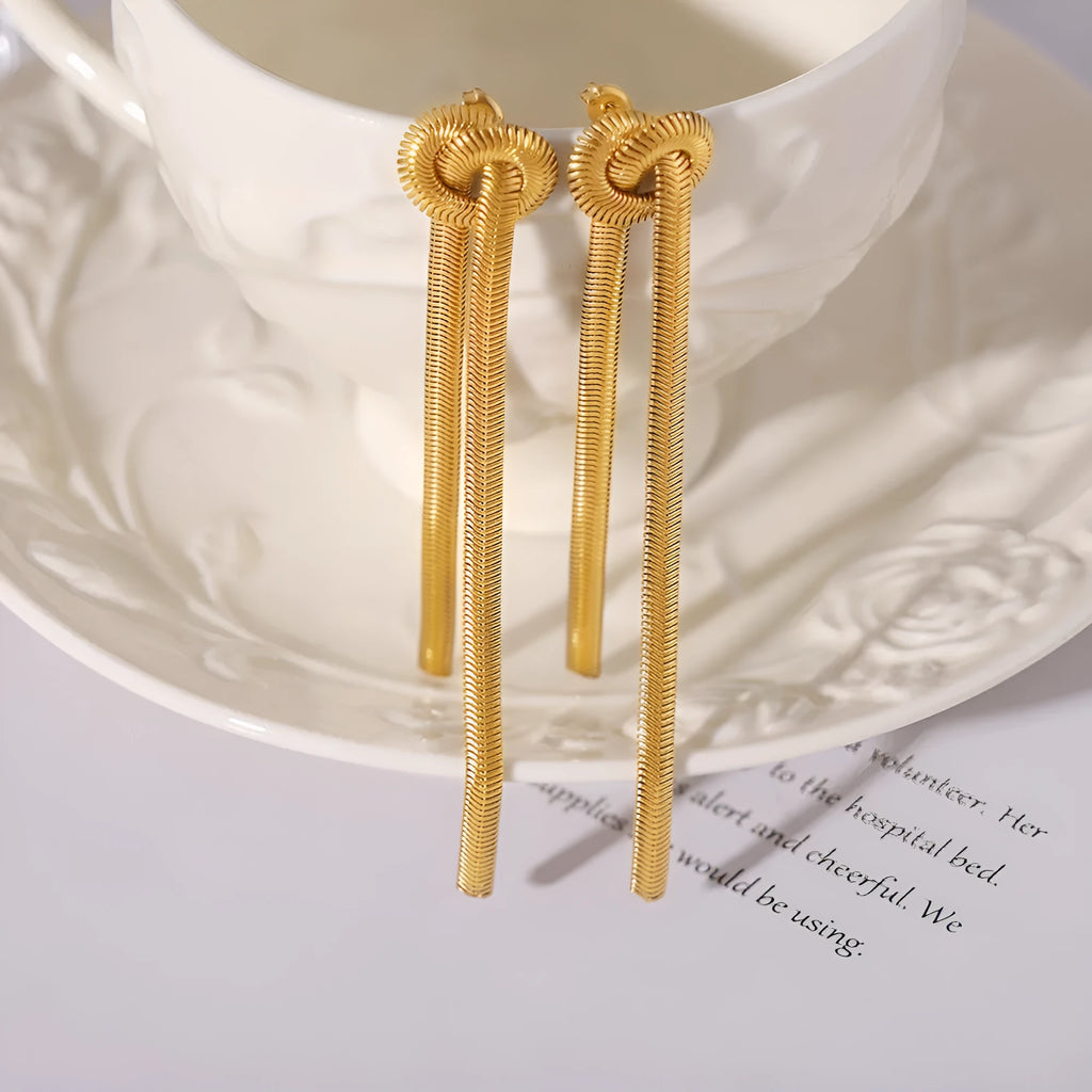 Gold colour titanium steel necklace with knotted tassel pendant and matching earrings on a white background.
