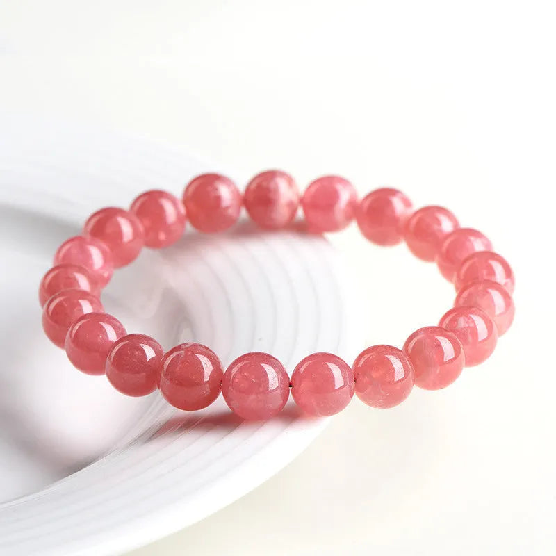 Women's red rhodochrosite crystal bracelet with geometric beads and a Longevity Lock charm.