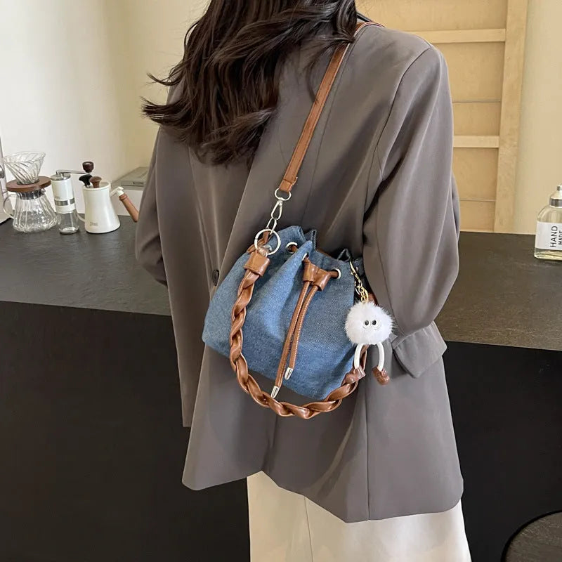 Blue synthetic leather cross body bucket bag with medium-soft structure and optional hanging ornaments