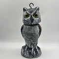 Artificial owl bird scare decoy ornament with a shaking head, shown in a garden setting.