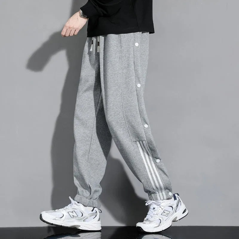 Man wearing black high-waisted, loose, ankle-tied sweatpants with a belt, showing the drawstring waist.