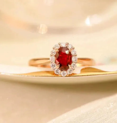 Silver ladies ring with blood ruby gemstone, gold pigeon inlay, and floral pattern design.