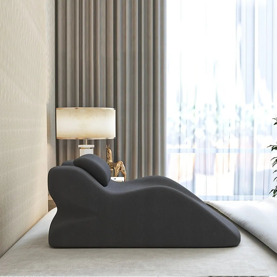 A flat stomach sleeper pillow shown on a bed, designed for prone sleeping and reading.