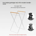 Black iron garbage storage hanger with wooden handle mounted on wall holding bin