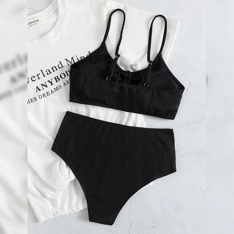 Black women's bikini swimsuit with sling top and high-waisted shorts on a white background