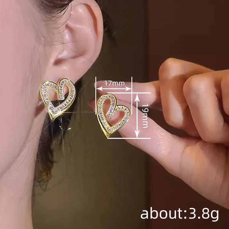 Hollowed heart shape ear studs in yellow gold tone copper with inlaid zircon detail