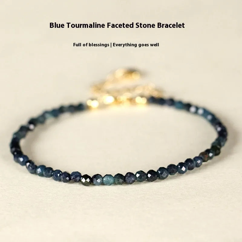 3mm blue tourmaline cut bead bracelet with gold spacer beads on wrist