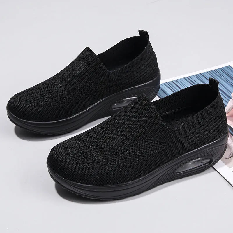 Women's black mesh running shoes with air cushion sole and round toe on a grey background.