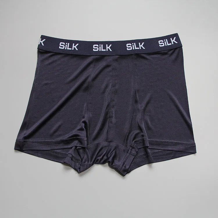 Men's loose-fitting silk shorts in navy blue, shown laid flat to display mid-waist design.