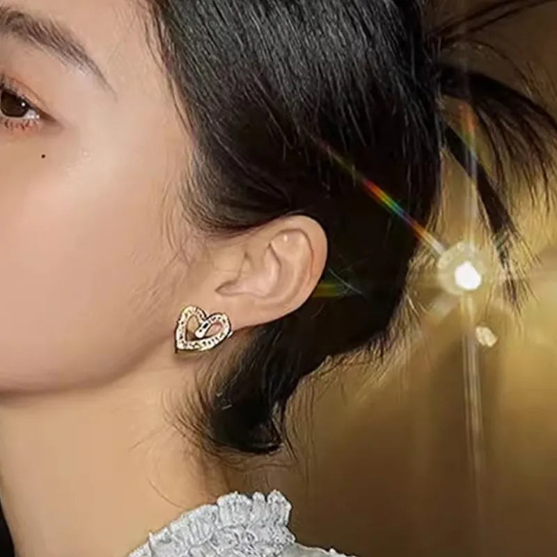 Hollowed heart shape ear studs in yellow gold tone copper with inlaid zircon detail