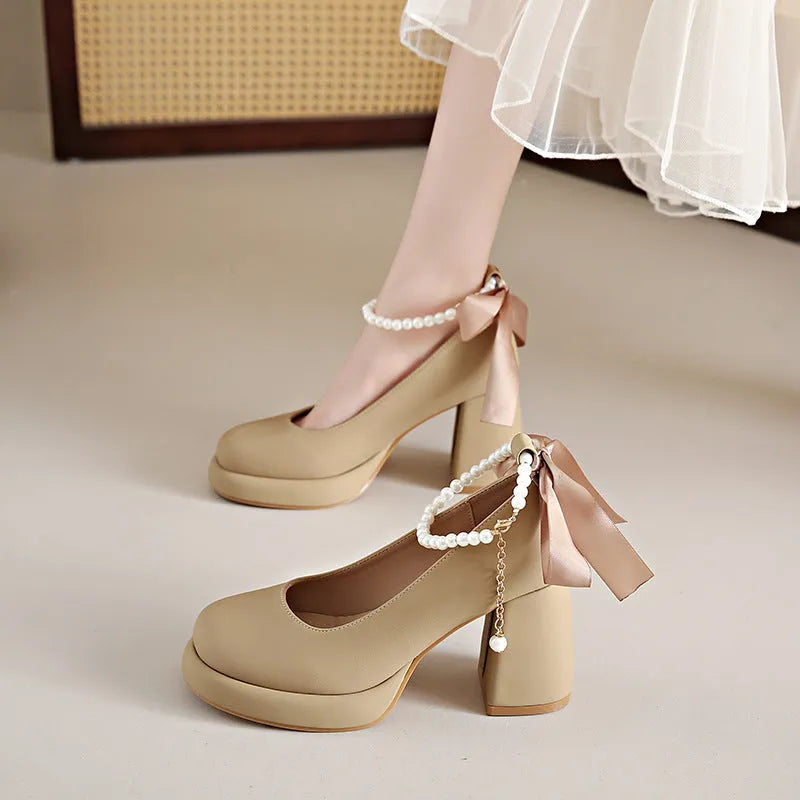 Women's beige Mary Jane shoes with a chunky heel and pearl-embellished ankle-strap buckle on a round toe.