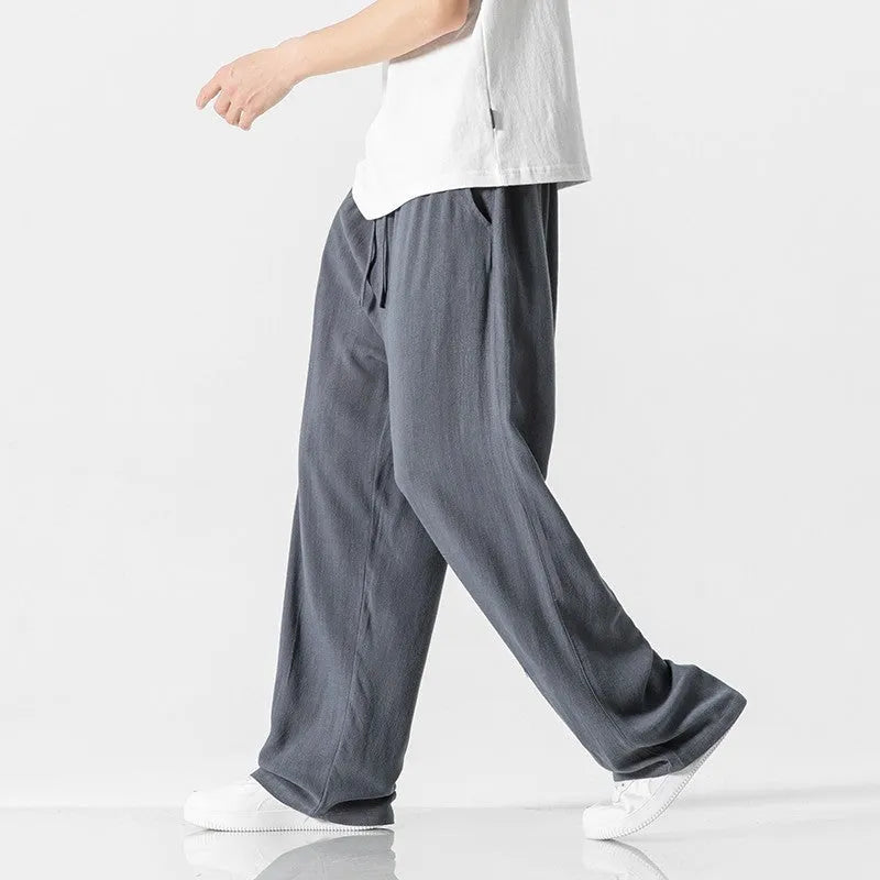 Man wearing beige straight-leg cropped linen trousers with a drawstring waist.