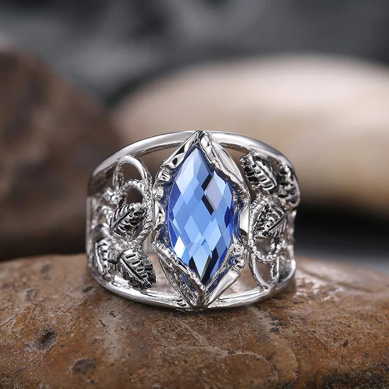 Blue crystal inlay horse eye-shaped geometric alloy ring for women on a plain background.