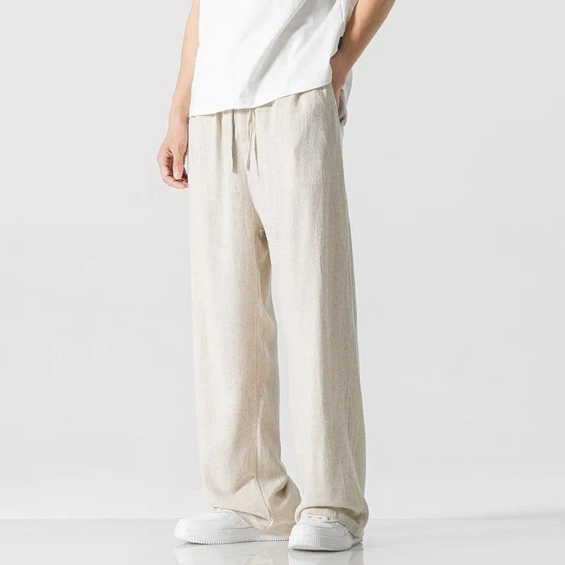 Man wearing beige straight-leg cropped linen trousers with a drawstring waist.