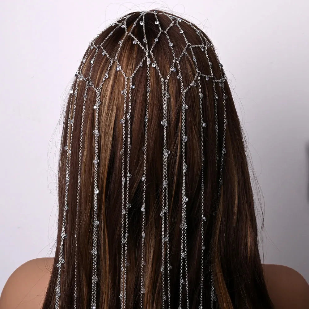 Gold coloured mesh headband decorated with rhinestones and a hanging tassel.