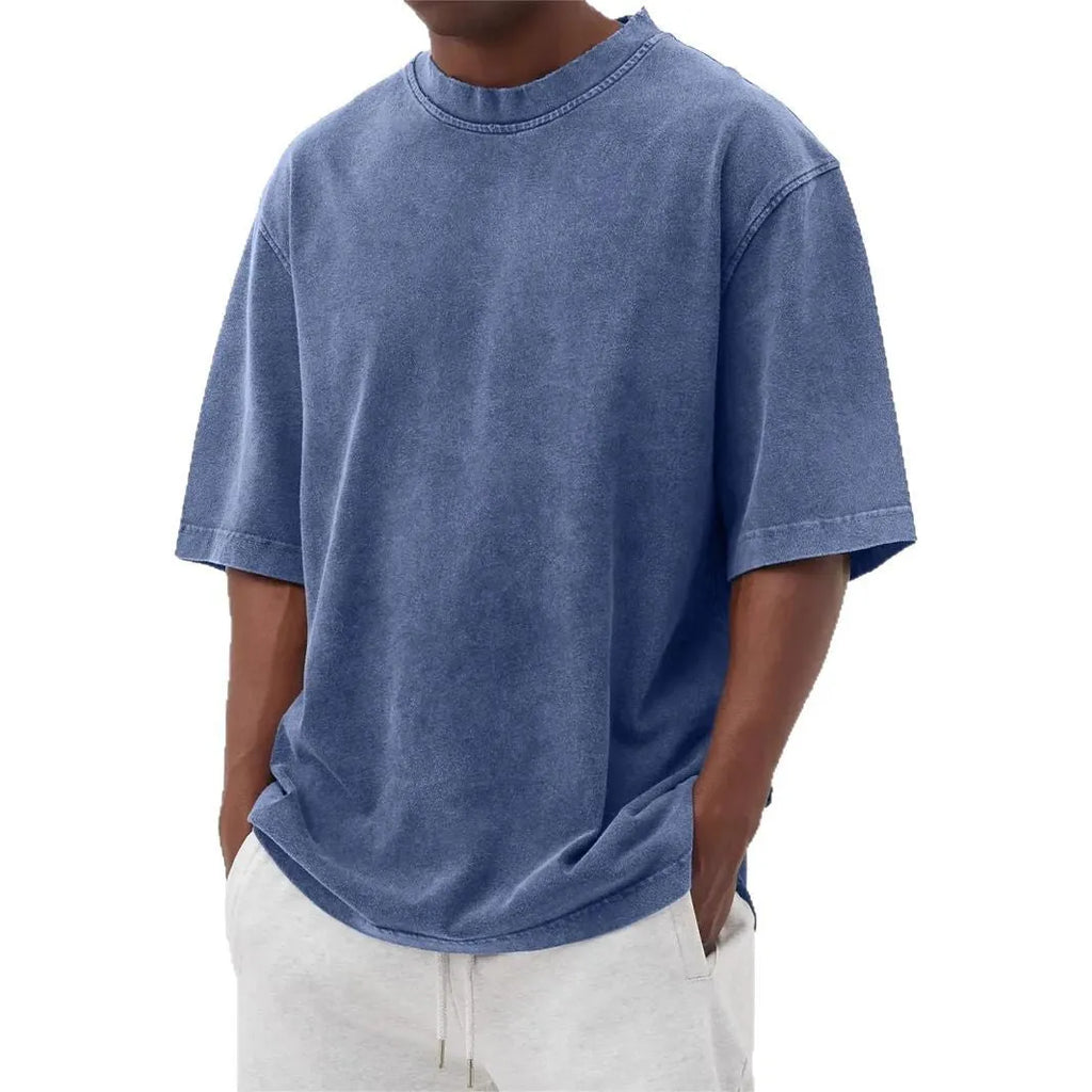 Man wearing a loose-fit, stone-washed distressed men's short sleeve T-shirt in a solid colour.