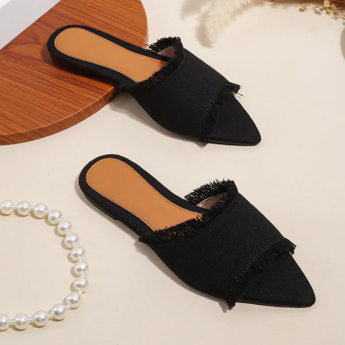 Women's denim flat slippers with tassel decoration in apricot colour on a white background.