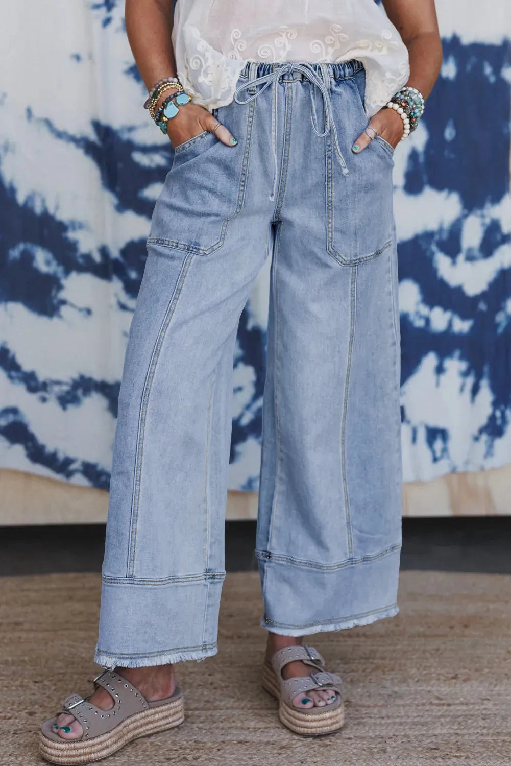Beau blue women's wide-leg denim trousers with a drawstring waist and raw hem detail laid flat.