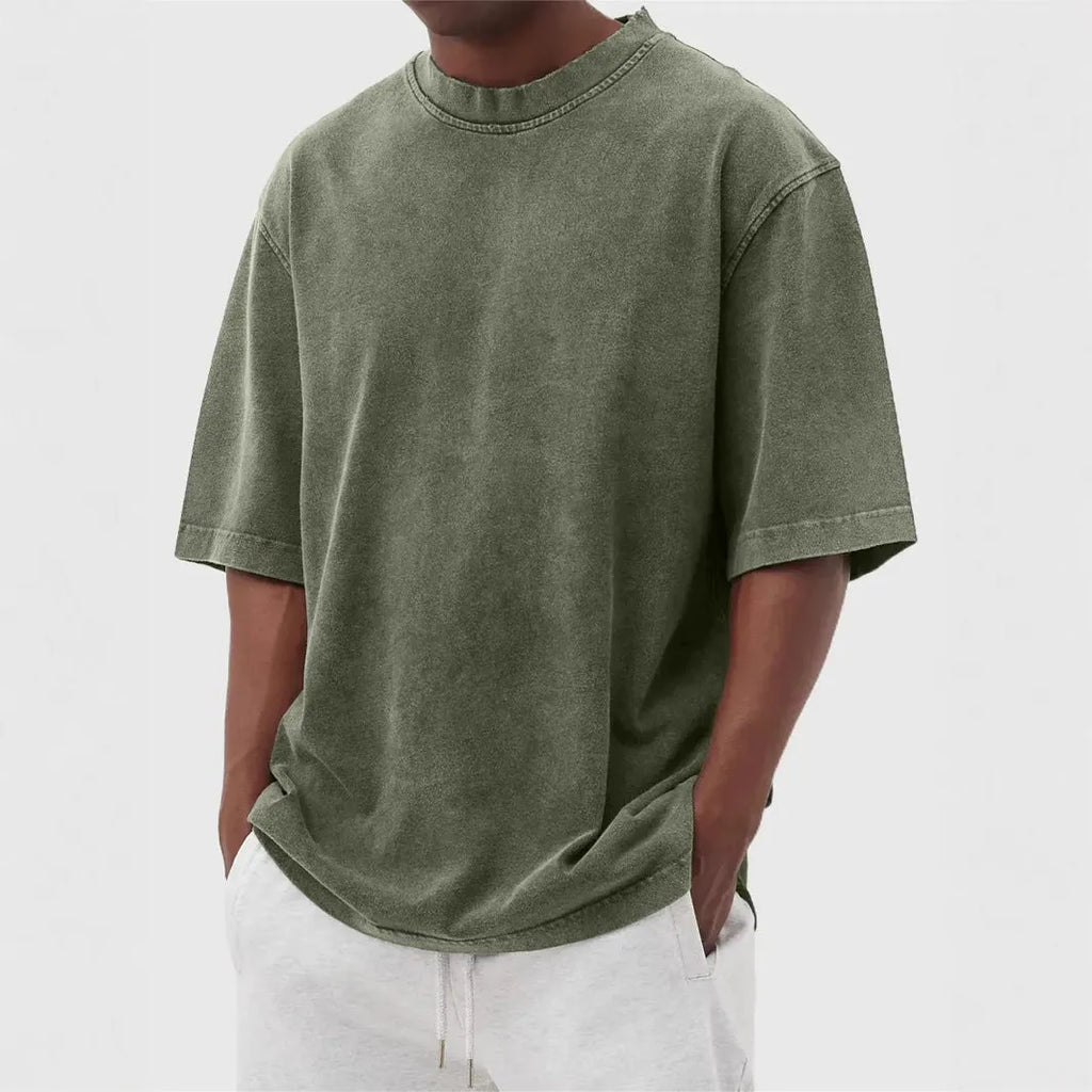Man wearing a loose-fit, stone-washed distressed men's short sleeve T-shirt in a solid colour.
