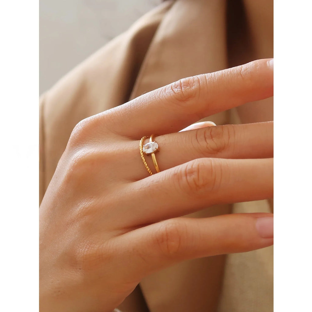 A golden stainless steel ring showing both the love heart design and the oval design option on a hand.
